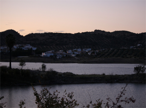 El pueblo situado a las orillas del embalse. Sus típicas casas blancas contrastan con el fondo del olivar.